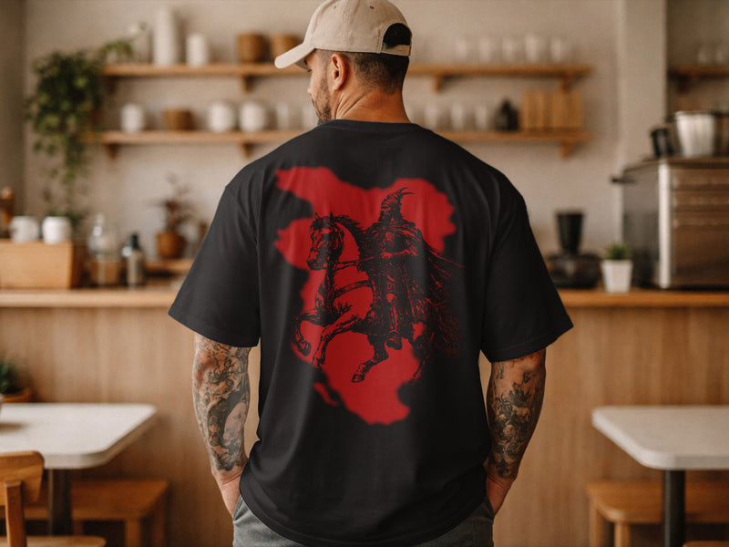 Person wearing a black t-shirt with a red and black graphic design in a kitchen setting